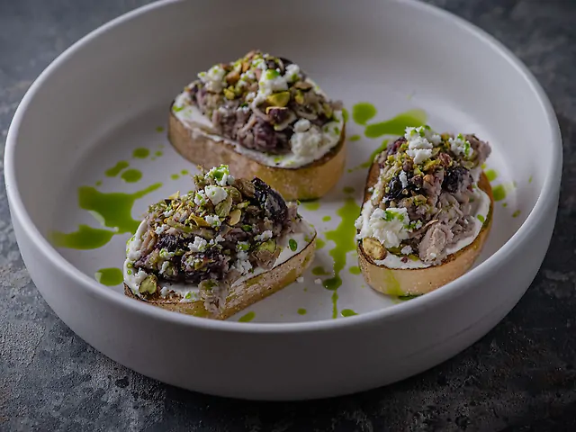 Брускети з фермерською куркою конфі з вишнями, рікотою, крем-сиром та фіста