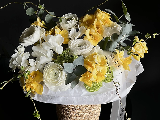 Композиція у кошику з фрезії, вібурнуму, ранункулюсів, евкаліпту та гілок