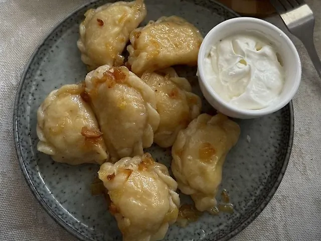 Вареники з картоплею, подаються зі шкварками та сметаною