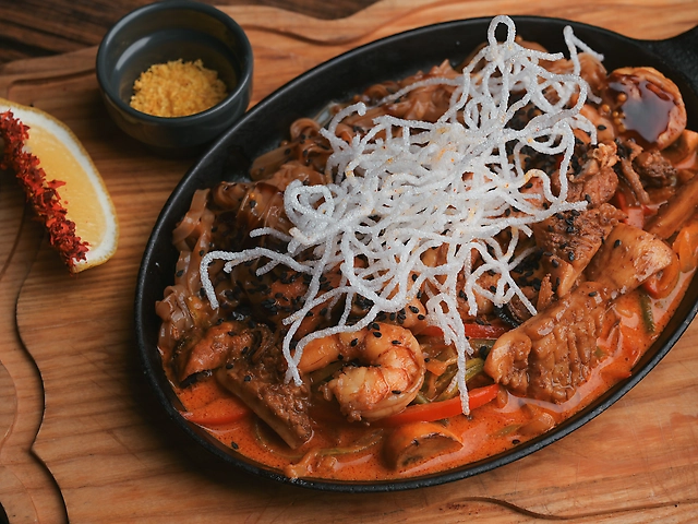 Пательня з морепродуктами, рисовою локшиною та овочами в соусі Том Ям